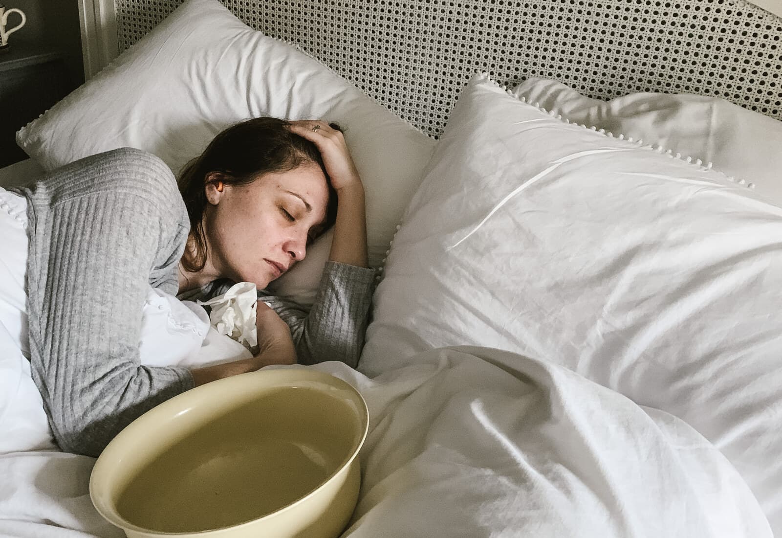 A woman experiencing severe pregnancy sickness resting in bed